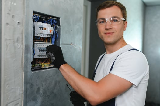 A male electrician works in a switchboard with an electrical connecting cable photo