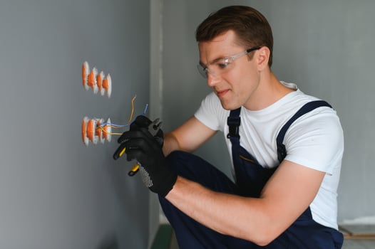 Electrician technician with gloves and safety instruments fixes the electric cable to the socket of a residential installation. photo