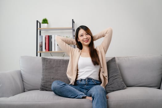 A portrait of beautiful young asian woman is sitting on a couch and smiling. photo