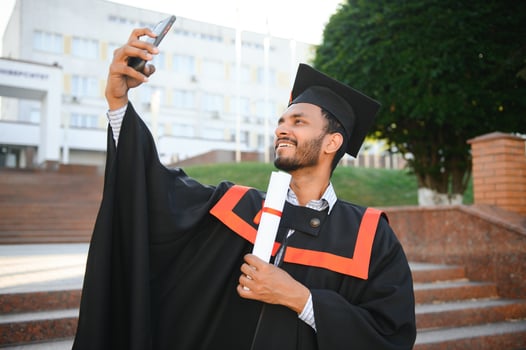 College graduate taking a selfie with cell phone holding a diploma. photo