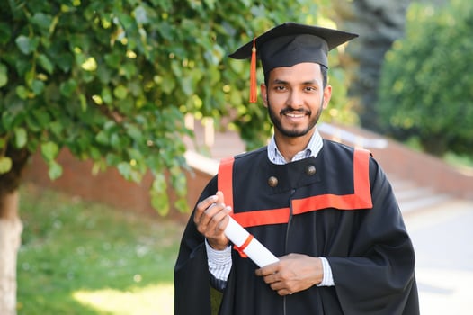 Portrait of indian handsome male graduate in graduation robe. photo