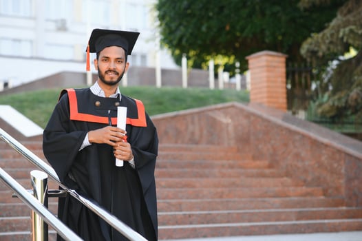 Portrait of indian handsome male graduate in graduation robe. photo