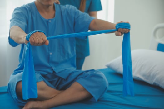 Close up hand patient doing stretching exercise with a flexible exercise band and a physical therapist hand to help in clinic room. photo