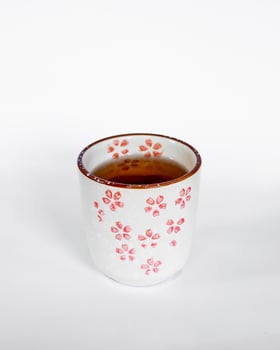 Black tea in a traditional Chinese or Japanese style ceramic cup with a cherry blossom pattern photo