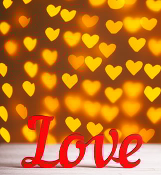 the inscription Love on a wooden background with beautiful hearts made of lights on a blurred background photo