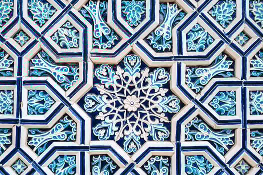uzbek tile mosaic with traditional oriental Arabic Islamic pattern decorated with blue and white ornament in wall in Uzbekistan photo