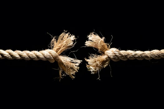 Frayed rope against black background, creating high tension photo