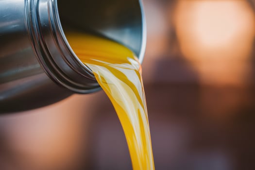 Metallic container pouring golden liquid, warm hues in blurred background photo