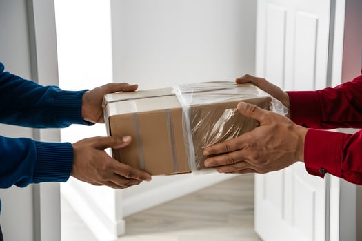 Hands exchanging cardboard box in well lit indoor setting, white background photo