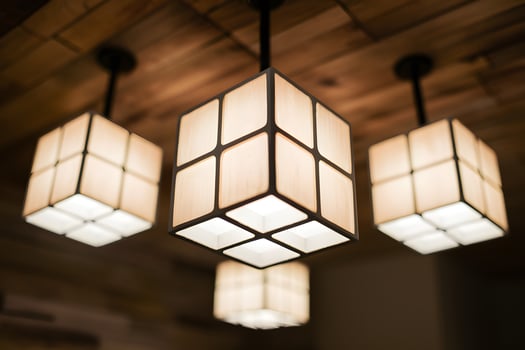 Three cube shaped light fixtures with central one illuminated, blurred wooden background photo