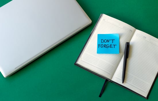 sticker reminder don't forget in notebook, laptop keyboard and open notebook on beautiful green background photo