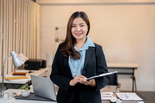 A beautiful Asian businesswoman is holding a clipboard paper, standing in the office. photo