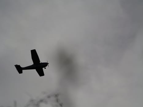 a small airplane flying through a cloudy sky photo