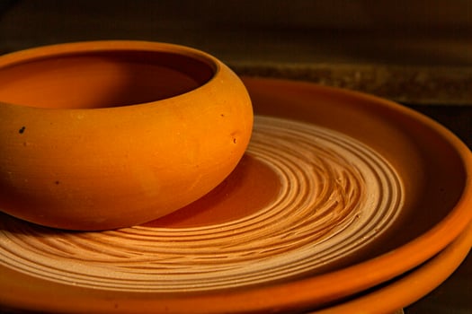 Freshly made clay mugs, pots and bowls drying up on wooden shelves in pottery workshop. Handmade ceramics manufacture. Different clay pots in workshop. photo