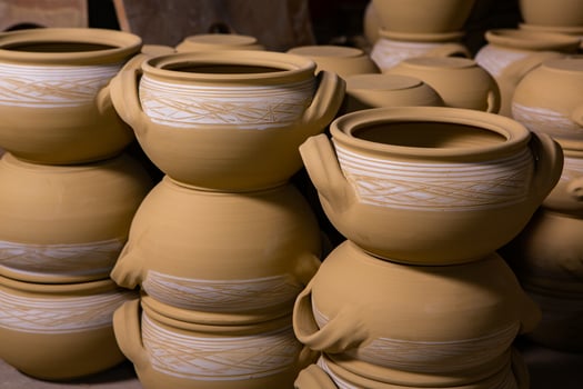 Freshly made clay mugs, pots and bowls drying up on wooden shelves in pottery workshop. Handmade ceramics manufacture. Different clay pots in workshop. photo