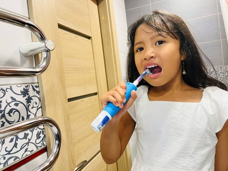 A happy little Asian girl brushes her teeth in the bathroom. Morning routine. Hygiene. Healthy lifestyle photo
