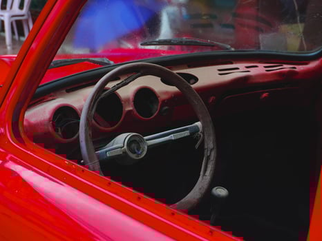 June 26 2024, Vientiane, Laos - Close-up of the steering wheel of an old red Volkswagen car parked on the sidewalk on the side of a country road. photo