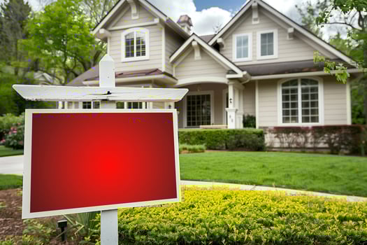 Empty Board Sign for Text. House for Sale with Red Blank Real Estate Sign in Front Yard, White Fence, Green Lawn, Spring Trees, and Sunny Sky photo