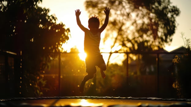 a child jumping on a trampoline at sunset photo