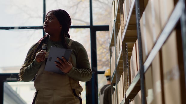 BIPOC warehouse stocker performing inventory survey, keeping quality standards high. Productive expert in distribution center preparing to ship parcels, crosschecking shippment info photo