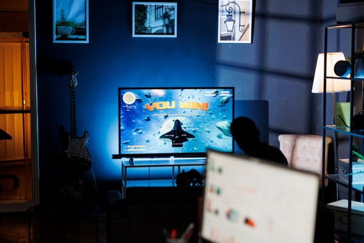 Happy gamer celebrating shooting contest victory, playing games on television in the living room. Adult feeling joyful after winning online first person tournament, leisure activity. photo