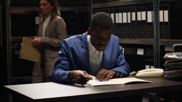 African american inspector conducts investigation, collecting evidence and examining case details. Close-up shot of private detective devotedly analyzing confidential suspect profile and information. photo