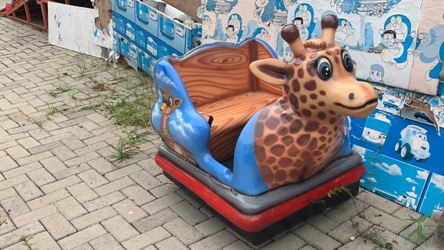 Giraffe riding in a toy car, closeup of photo