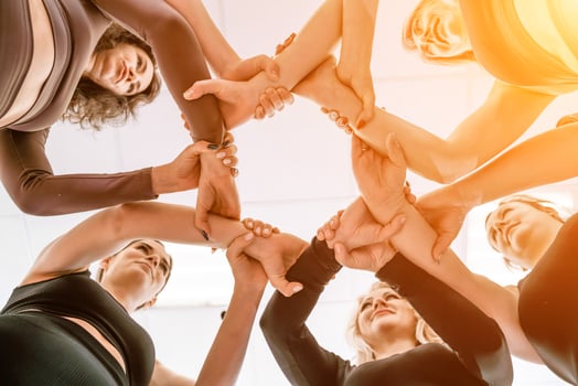 Team of people holding hands. Group of happy young women holding hands. Bottom view, low angle shot of human hands. Friendship and unity concept photo