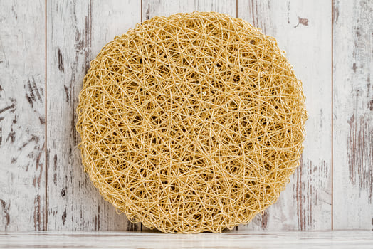 Round, Yellowish Golden Mat with a Textured Surface on White Background photo