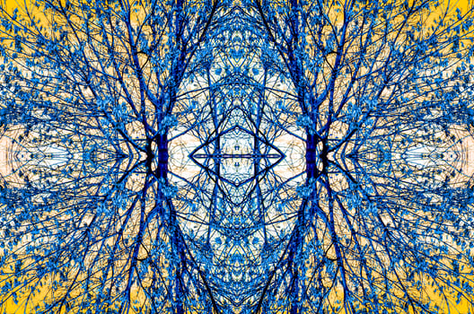 Symmetrical, kaleidoscopic image of tree branches with blue leaves against a yellow sky, creating an abstract and intricate pattern. photo