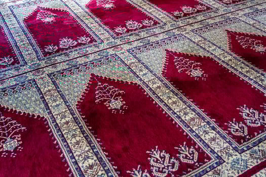 Close up of a traditional red and white patterned carpet with intricate designs, in a mosque, Turkey. photo