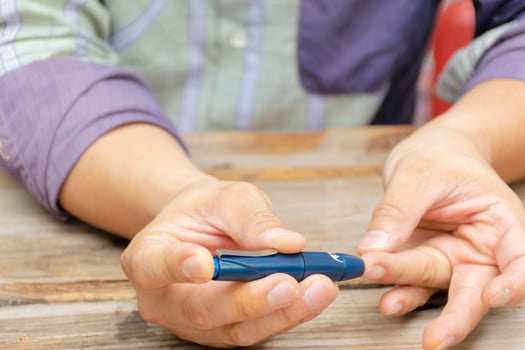 Man taking blood sample with lancet pen indoors. Diabetes concept. photo