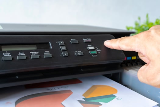 Fingers that are pressing the button, The printer is fully functional,Located on the desk. photo