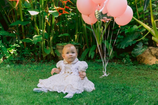 Birthday of baby girl with air balloons in outdoor garden. Happy child in dress. photo