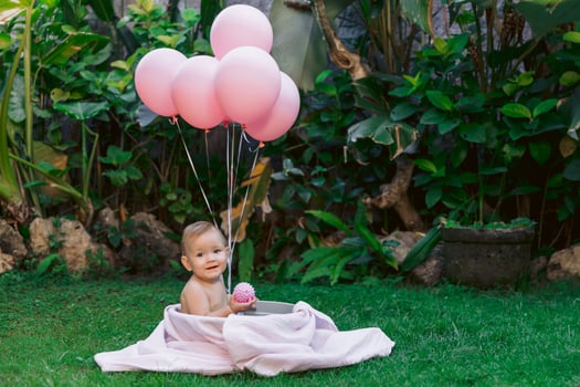 Baby girl and pink air balloons swim in baby bath outdoor garden. Happy baby. photo