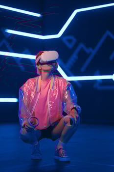 Young female gamer in pink is playing virtual reality games. VR headset and controllers. photo