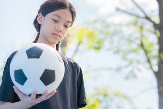 Kid girl with a soccer ball, Asian child girl playing football in the urban outdoor futsal court photo