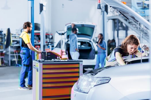 Mechanic in car service picking torque wrench from work station bench, using it to tighten bolts after replacing battery. Qualified garage worker uses professional tools to fix client automobile photo