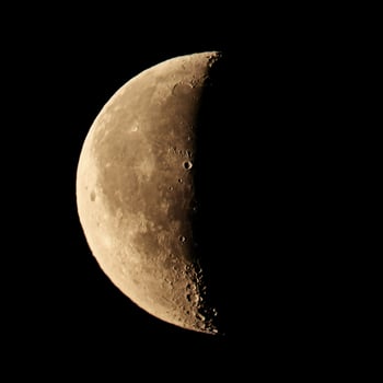 Close up view on a yellow half disk of the moon on a black sky background photo