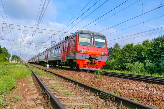 Bottom view on the approaching passenger electric train against a blue sky and green forest photo