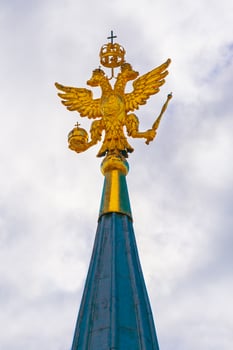 Golden coat of arms, two-headed eagle, of Russian Federation on the top of Kremlin tower against of a gray overcast sky photo