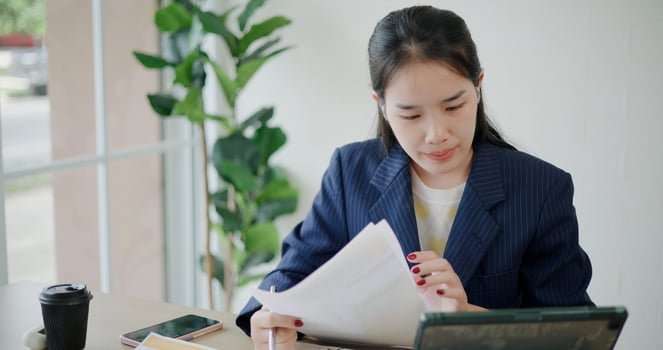 Portrait of Asian businesswoman in suit use digital tablet for work and analyze documents in small coffee shop. Work from anywhere, Remote working photo
