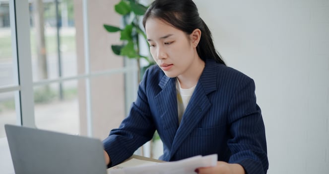 Portrait of Asian businesswoman in suit use laptop for work and analyze documents in small coffee shop. Work from anywhere, Remote working photo