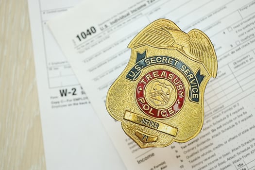KYIV, UKRAINE - MARCH 9, 2024 US Treasury Police Secret Service Officer badge on 1040 and W-2 IRS tax forms photo