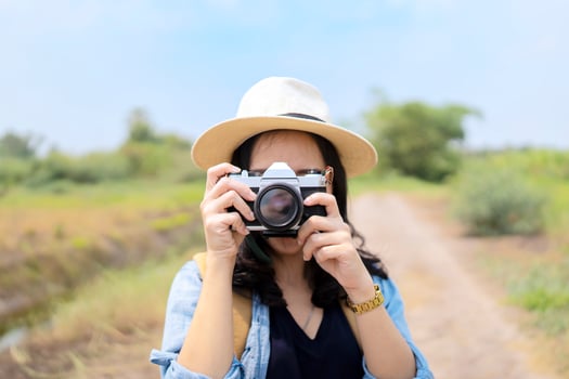 Young asian girl taking photo outdoors with camera