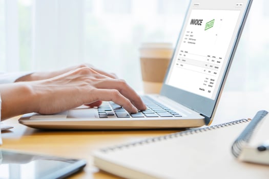 A Businessperson's Hand Checking Invoice On laptop At Workplace photo