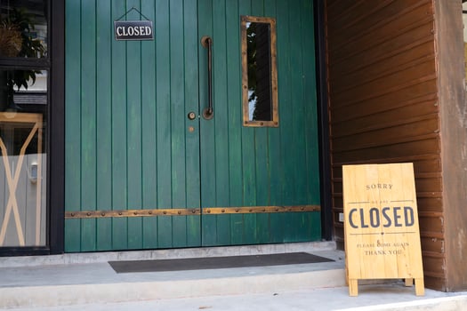 Closeup Wooden sign placed in front of the shop is labeled SORRY WE'RE CLOSED photo