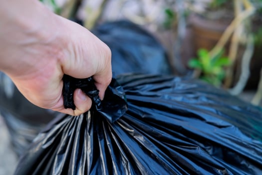 young man taking out garbage in black plastic bag photo