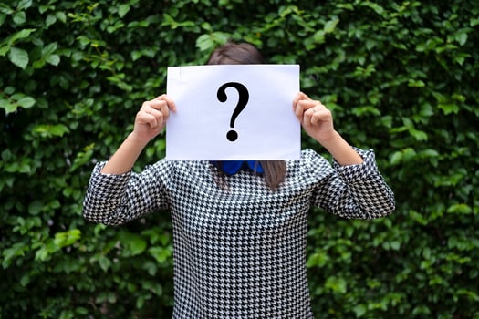 Asian Woman Holding Paper With Question Mark, The background is a leaf wall. photo