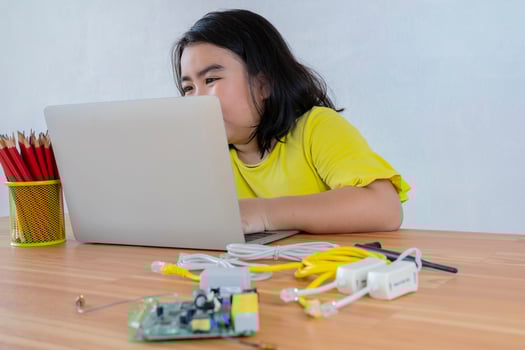 An Asian girl uses a laptop to install a robot controller from a plastic brick. Origins of education for children. STEM Education for kids. photo